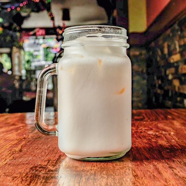 A refreshing glass of Horchata, a traditional Mexican drink, on a rustic wooden table.
