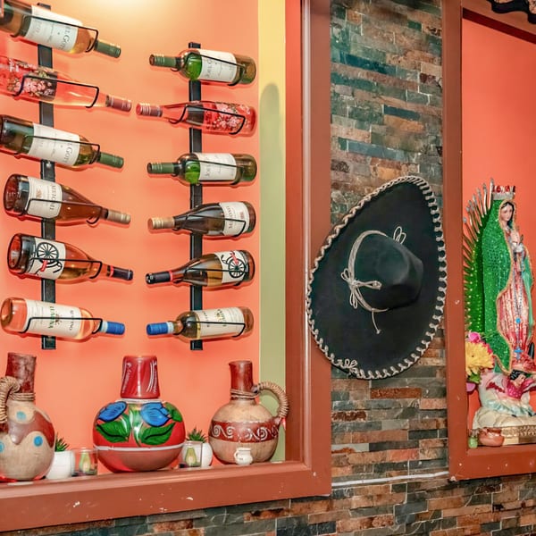 Wine bottles on a wall rack, a sombrero, and a Virgin Mary statue in a Mexican restaurant.